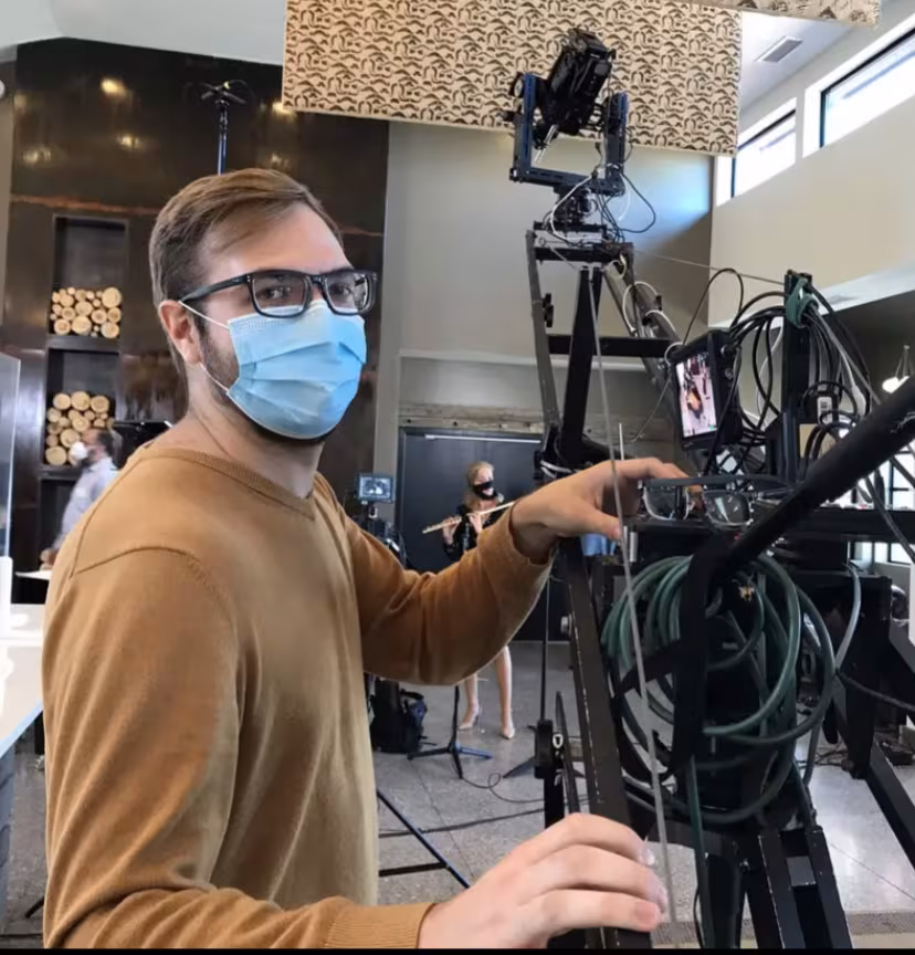Crew member operating a camera crane during an indoor live music performance