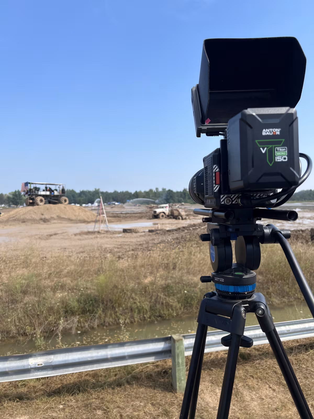 Cinema camera on a fluid-head tripod overlooking an active construction site