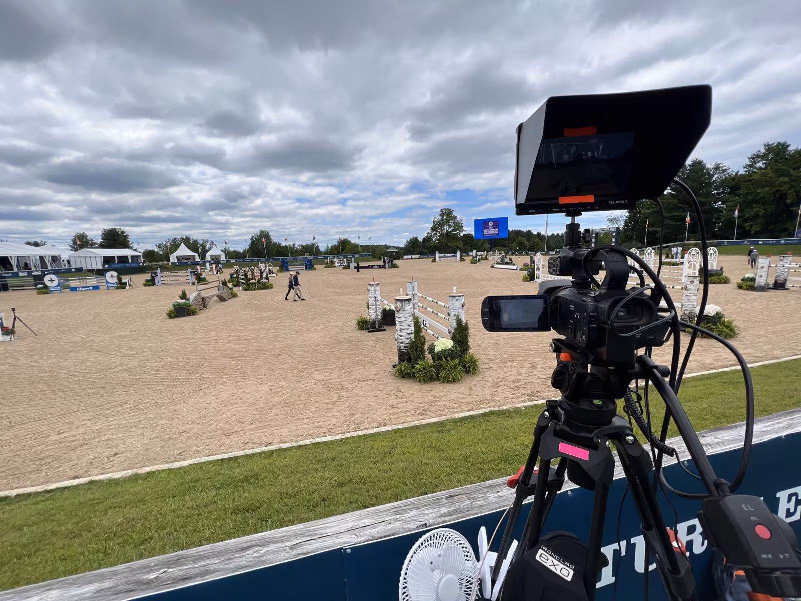 Broadcast camera positioned above an outdoor equestrian show jumping arena