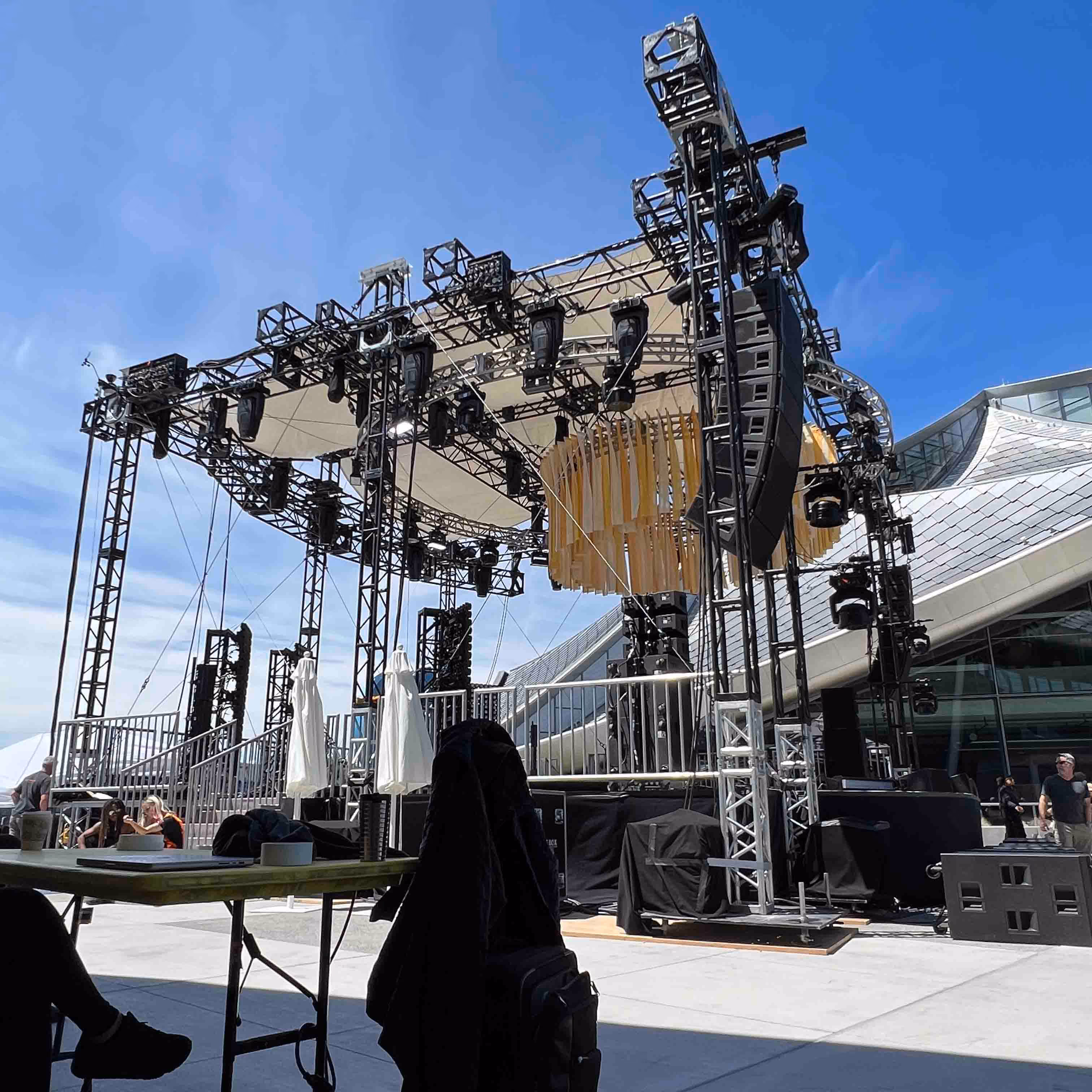 Outdoor stage setup with lighting and speakers under clear blue sky